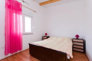 sypialnia z łóżkiem i oknem z różowymi zasłonami w obiekcie House Maslina w Medulinie