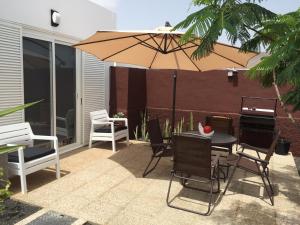 eine Terrasse mit einem Tisch, Stühlen und einem Sonnenschirm in der Unterkunft Villa Benita II in Playa Blanca