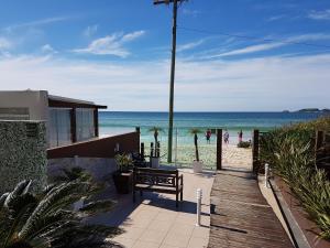 a wooden walkway to the beach with a bench at Palm Beach Apart Hotel - Pé na Areia in Florianópolis
