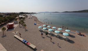 a beach with a bunch of umbrellas and people on it at Apartments Zelic in Vodice