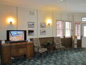a waiting room with a flat screen tv and chairs at Triple J Hotel in Dawson City