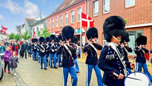 a marching band in uniforms walking down a street at Det Gamle Rådhus in Gråsten