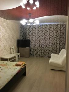 a bedroom with a bed and a chair and a tv at Apartment Ozernaya 7 in Tver