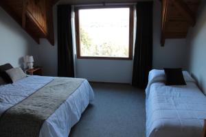 a bedroom with two beds and a window at Peninsula de los Coihues in Villa Pehuenia