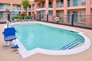 a swimming pool at a hotel with a blue chair and a chair at Americas Best Value Inn Clute in Clute