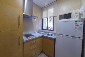 a small kitchen with a white refrigerator and a sink at La Torre in Córdoba