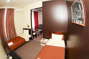 モスクワにあるホテル オリンプのベッド2台と椅子が備わる小さなホテルルームです。