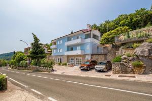 ein blaues Gebäude mit Autos, die an einer Straße geparkt sind in der Unterkunft Apartments Gea in Mošćenička Draga