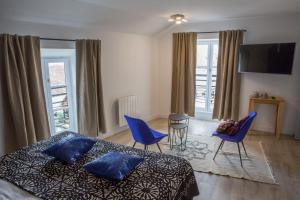 a bedroom with a bed and chairs and a television at Douce Nuits in Nuits-Saint-Georges