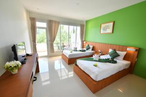 1 dormitorio con 2 camas, escritorio y TV en The Touch Green Naiyang Hotel & Fitness en Nai Yang Beach