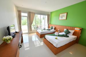 a bedroom with two beds and a desk and a television at The Touch Green Naiyang Hotel & Fitness in Nai Yang Beach