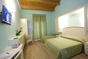 a hotel room with two beds and a desk at Hotel Da Angelo in Assisi