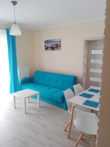 a living room with a blue couch and a table at Apartamenty "u Jasia" I in Darlowko