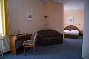 a hotel room with a chair and a desk and a bed at Weser Wasserbetten Hotel Baxmann in Hessisch Oldendorf