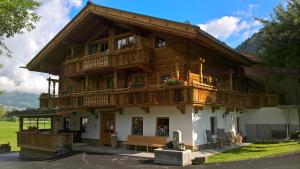 a large wooden house with a balcony and a bench at Häuserhof in Stumm