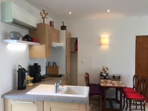 a kitchen with a sink and a table with chairs at Gîte climatisé de La Haute Rue in Touvois