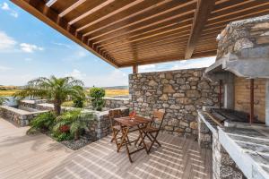 a patio with a table and a stone wall at Prasonisi Villas in Kattavía