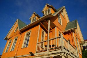 an orange house with a balcony and a blue sky at Hotel Brighton in Valparaíso