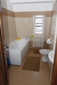 a bathroom with a tub and a toilet and a sink at Central apartments - Red in Bacău