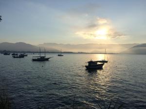 eine Gruppe von Booten im Wasser bei Sonnenuntergang in der Unterkunft Kitchenette Charmosa no Itagua in Ubatuba