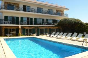 un hotel con piscina, sillas y un edificio en Vivenda Solmar, en Lagos