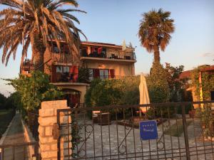 a building with palm trees and a gate with an umbrella at Apartments Plazs 41 in Sukošan