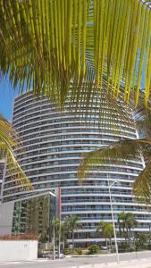 a large building with a palm tree in front of it at Apart-Hotel Terraços do Atlântico in Fortaleza