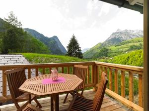 a table and chairs on a wooden deck with mountains at Bauernhof Wildfang in Dalaas