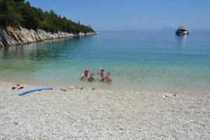 a group of people sitting in the water on a beach at Aristotelis Apartments in Frikes