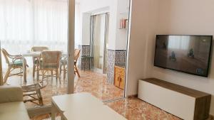 sala de estar con TV y mesa con sillas en Andalusian Apartment, en Marbella