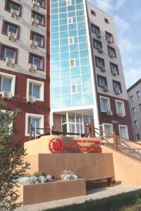 a tall building with a sign in front of it at Manhattan Astana Hotel in Astana