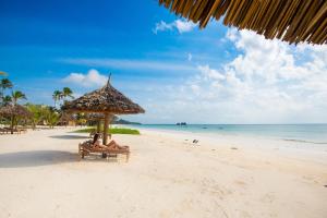 zwei Personen am Strand unter einem Sonnenschirm in der Unterkunft The Sands Beach Resort in Bwejuu