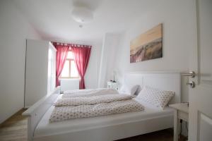 a white bedroom with a white bed and a window at Ferienwohnungen EULE in Lutherstadt Wittenberg