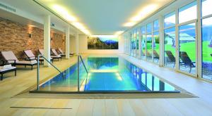 an indoor swimming pool in a building with windows at Hotel Achentalerhof in Achenkirch