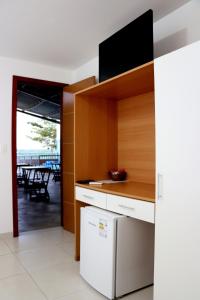 a kitchen with a white refrigerator and a table at Pousada Solar das Conchas in Santa Cruz