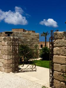 une porte en fer dans un mur en pierre avec un palmier dans l'établissement Il Baglio sull'Acqua, à Favignana