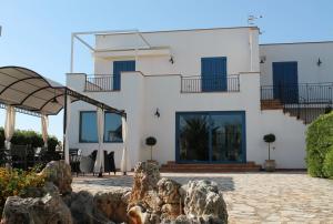 a white house with blue windows and a patio at Case Selinuntine Apartments in Marinella di Selinunte