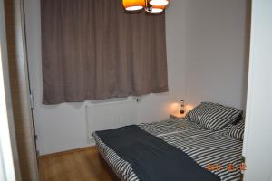 a small bedroom with a bed and a window at GÓBÉ Apartman in Hajdúszoboszló