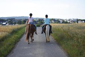 two women riding on horses down a road at Landhof Lieg - Tierische Auszeit in unseren gemütlichen Ferienwohnungen in Lieg