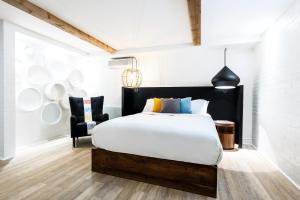 a bedroom with a large bed and a chair at C3- Hotel Art De Vivre in Quebec City