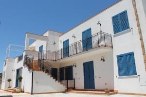 a white house with stairs and blue shutters at Case Selinuntine Apartments in Marinella di Selinunte