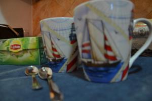 a coffee mug with a boat on it next to spoons at Bed & Breakfast Gli Alisei in Siniscola