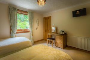 1 Schlafzimmer mit 2 Betten, einem Schreibtisch und einem Fenster in der Unterkunft Cairnryan Bed and Breakfast in Cairnryan