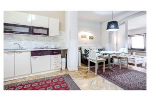 a kitchen and dining room with white cabinets and a table at Apartments and Rooms Fonty in Sarajevo