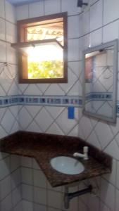 a bathroom with a sink and a mirror and a window at Pousada Ponta de Areia do Bixão in Itaúnas