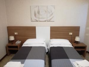 2 camas en una habitación pequeña con 2 lámparas en Hotel Mucciolini, en Castrocaro Terme