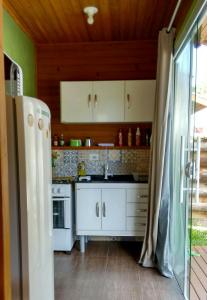 a kitchen with white cabinets and a refrigerator at Cabanas do Lorde in Praia do Rosa