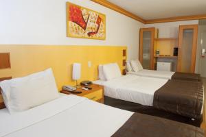 a hotel room with two beds and a clock on the wall at Planalto Bittar Hotel e Eventos in Brasilia +24 photos