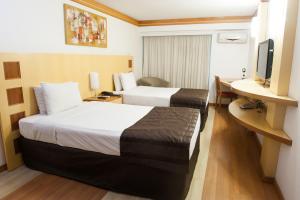 a hotel room with two beds and two lamps at Planalto Bittar Hotel e Eventos in Brasília