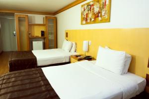 a hotel room with two beds and a mirror at Planalto Bittar Hotel e Eventos in Brasília